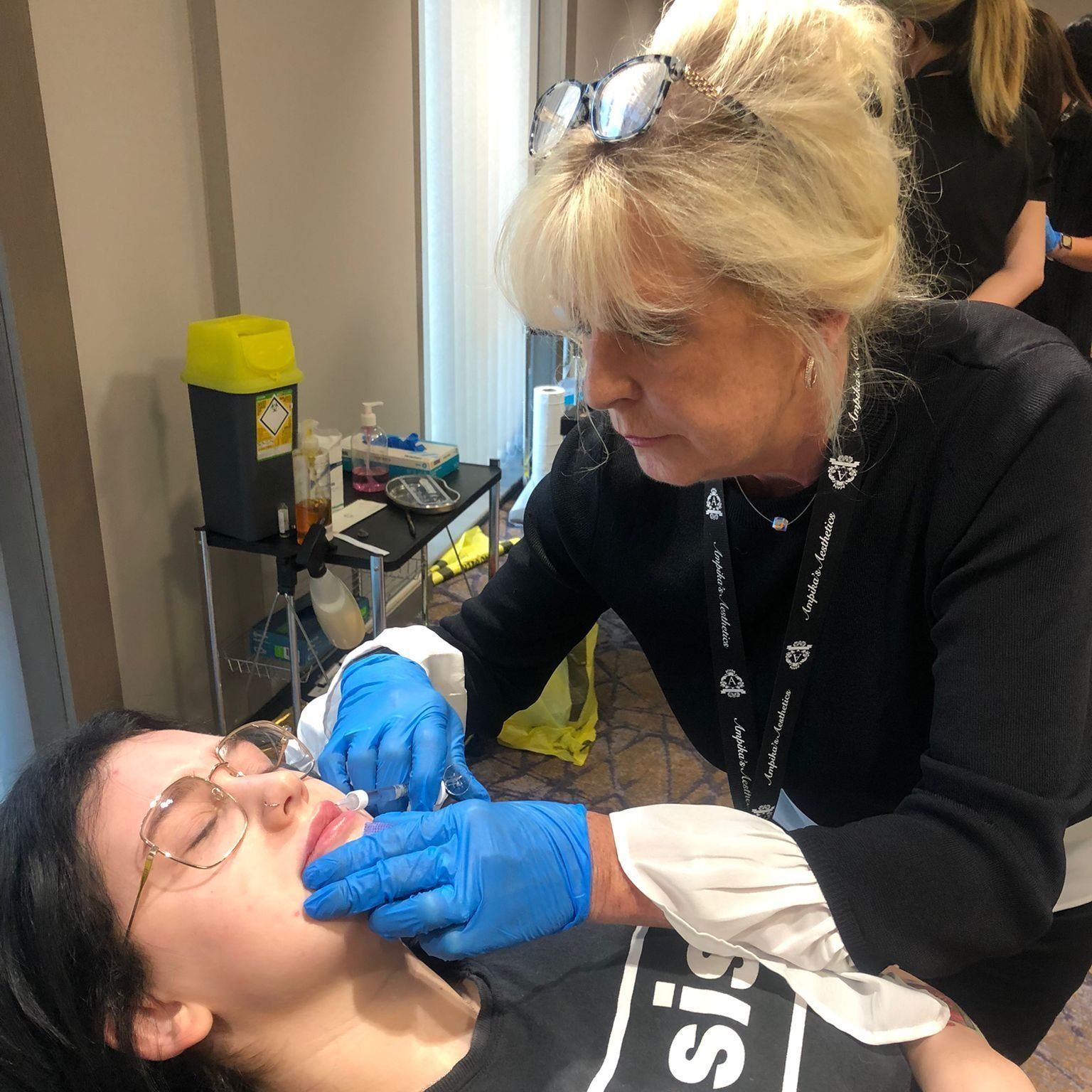 Mandy, in blue gloves, treating a client’s lips