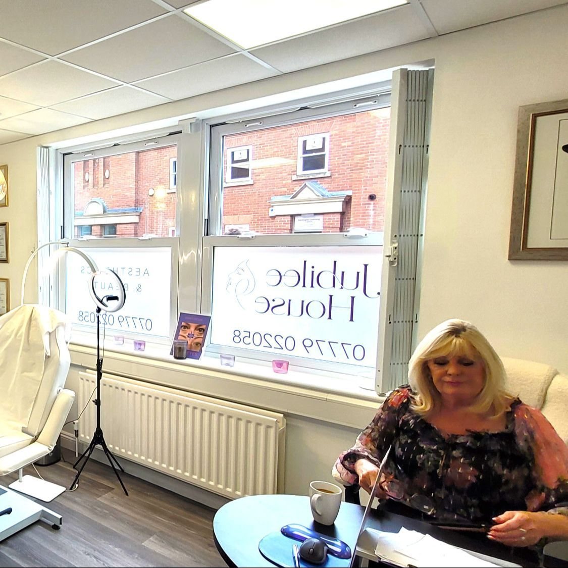 Mandy at her desk in the clinic, with the Jubilee House window lettering behind her