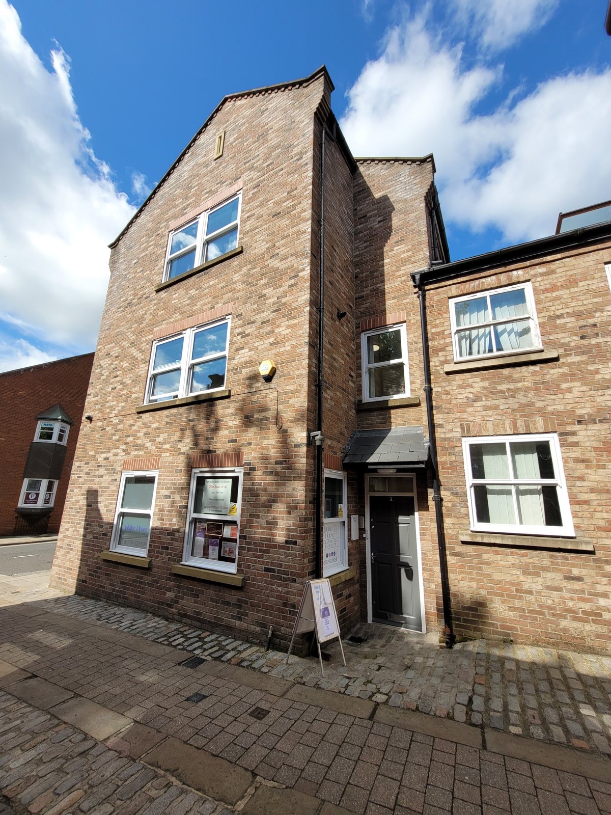 Jubilee House, a three storey brick building, seen from the lane