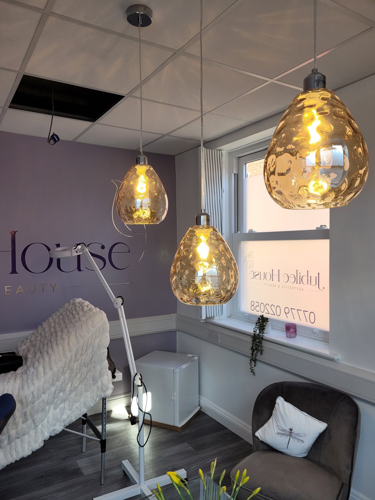 Amber glass pendant lamps above the treatment bed and a velvet chair