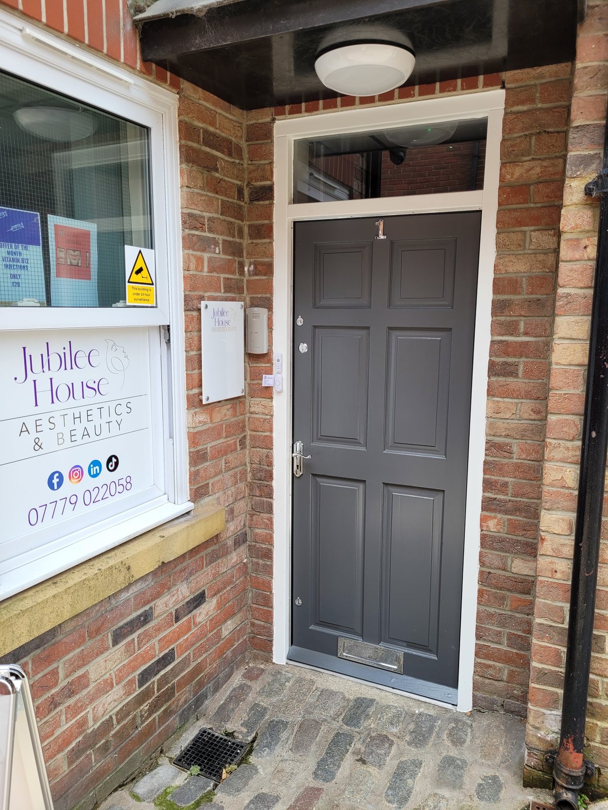 The front door, with the Jubilee House name and phone number in the window beside it